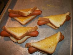 four pieces of toasted bread with hotdogs on them sitting on a baking sheet