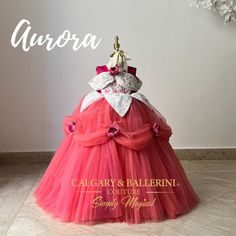 the dress is red and white with pink flowers on it's bust, while the word aurora written in gold reads