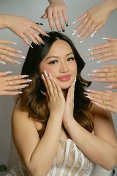 a woman with her hands on her face surrounded by many manies and nail polish