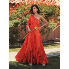 a woman in an orange dress standing on the grass