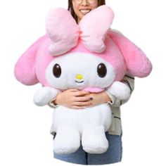 a woman holding a large pink hello kitty stuffed animal