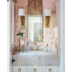 a bathroom with pink wallpaper and gold fixtures