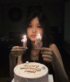 a woman holding two candles in front of her birthday cake with the number eight on it