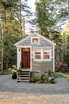 the tiny house is surrounded by trees and flowers