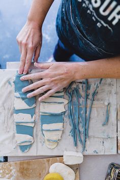 a person working on some art work with blue and white paint in the middle of it