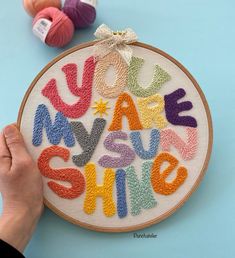 someone is stitching the letters on a colorful wallhanger with yarn and scissors