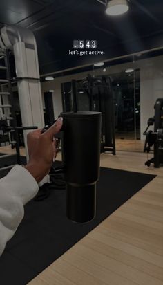 a person is holding a coffee cup in the middle of a gym with other equipment