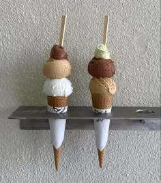 three ice cream cones are sitting on a shelf with two sticks sticking out of them