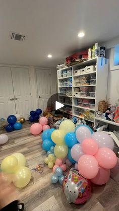 a room filled with lots of balloons and other items on the floor in front of shelves