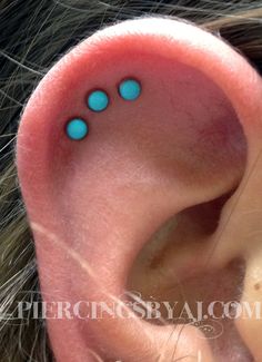 a woman's ear with three blue dots on it