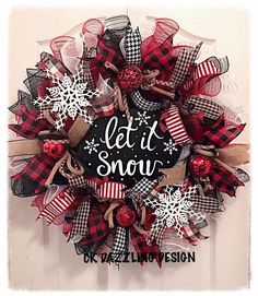 a red and black christmas wreath with snowflakes on the front door that says let it snow