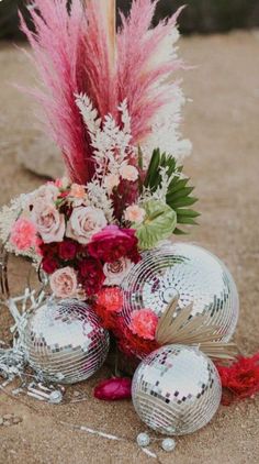 a vase filled with flowers next to disco balls and other decorations on the ground in front of some rocks