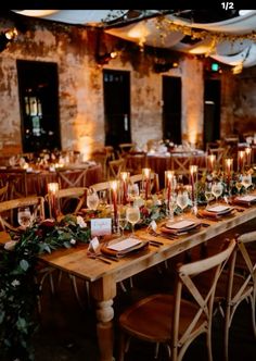 a long wooden table with candles and place settings on it in front of an old brick wall