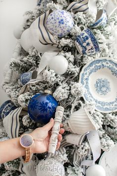 a christmas tree is decorated with blue and white dishes, ornaments, and silverware