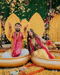 a man and woman sitting on top of a boat in front of a flower display