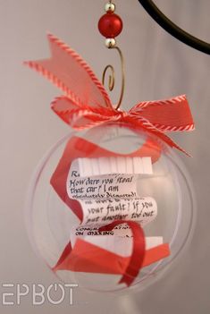 a glass ornament with red ribbon and some writing on it's side