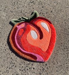 an orange and pink apple shaped rug on the ground