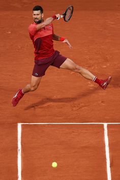 a tennis player is running to hit the ball with his racquet on a clay court