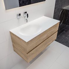 a white sink sitting under a bathroom mirror next to a wooden cabinet with two faucets