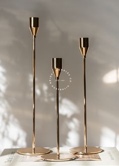 three brass candlesticks on top of a table