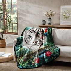 a white tiger sitting on top of a couch next to a table and potted plant