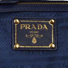 the prada bag is blue with gold trimmings and has a name tag on it