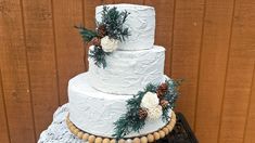 a white wedding cake with pine cones and flowers