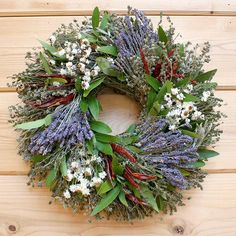 a wreath with lavenders and other flowers on a wooden surface, ready to be hung