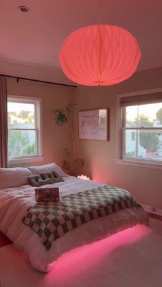 a bedroom with pink lighting and a bed in the middle is lit up by two lamps