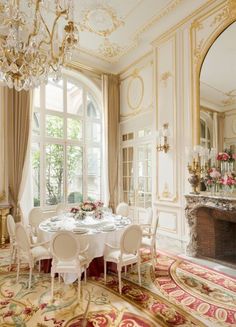 an elegant dining room with chandelier and table set for four people in front of a fireplace