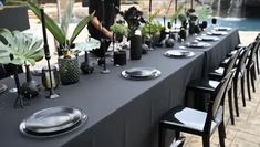 the table is set with black plates and silverware