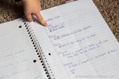 a child's hand is on top of a notebook with writing in the middle