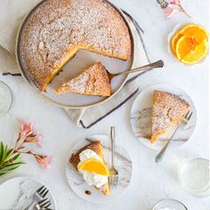 a table topped with slices of cake and orange wedges next to plates of food