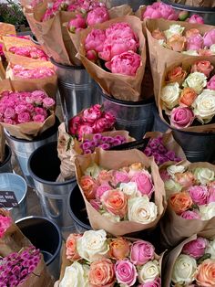 many different types of flowers are in buckets on the table and ready to be sold