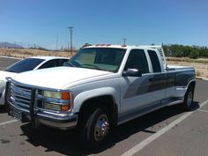 two white trucks parked in a parking lot next to each other on a sunny day