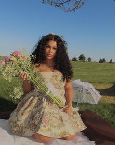 a woman sitting on the ground holding flowers