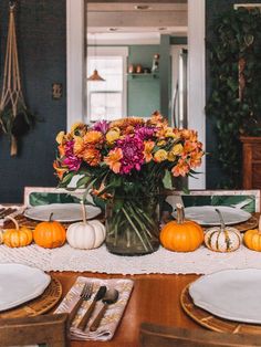 a vase filled with flowers sitting on top of a table next to white plates and silverware