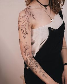 a woman wearing a black and white dress with tattoos on her arm, shoulder and chest