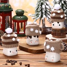 four coffee mugs decorated with knitted hats and snowflakes on a wooden table