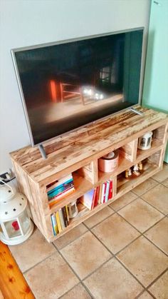 a television stand made out of pallet wood with books and magazines on the bottom shelf