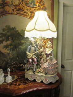 a lamp that is sitting on top of a table in front of a wall painting