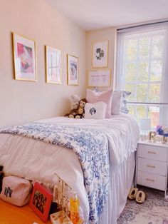 a white bed sitting next to a window with pictures on the wall above it in a bedroom