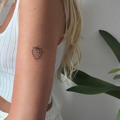 a woman with a small strawberry tattoo on her left arm and right arm behind her back