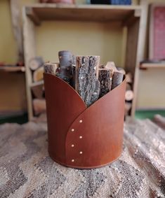 a brown leather cup filled with logs on top of a table