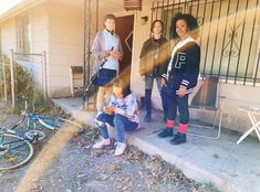 three young women standing in front of a house