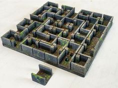 a model of a maze made out of bricks and concrete blocks with grass growing on the ground