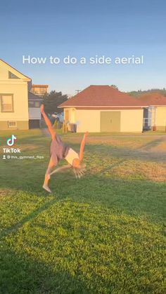 a person jumping in the air on top of a grass covered field next to a house