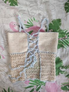 a piece of crocheted material on a bed with pink flamingos in the background