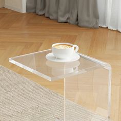 a glass table with a cup of coffee on it and a rug in the background