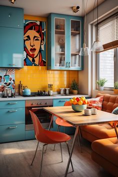 a kitchen with blue cabinets, orange chairs and a painting on the wall above the table